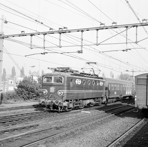 883133 Afbeelding van een electrische locomotief uit de serie 1100 van de N.S. met een een getrokken trein bij aankomst ...